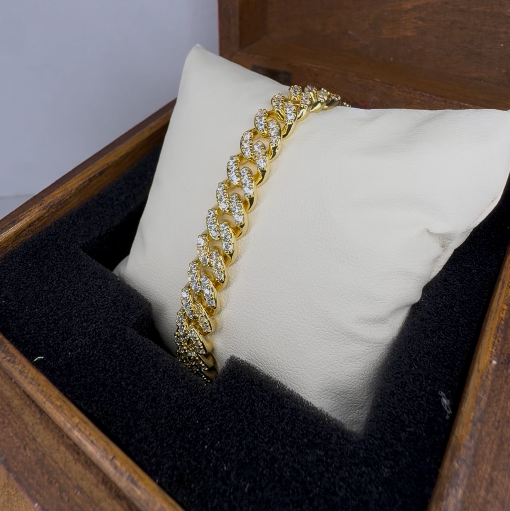 Gold bracelet on a white pillow inside a wooden jewelry box with a gray background
