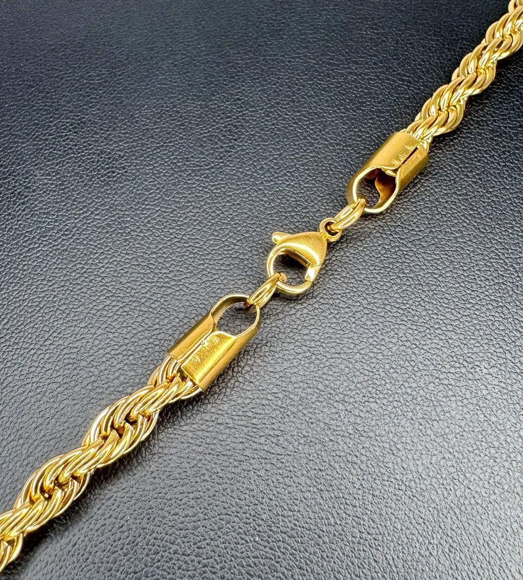 Gold rope chain necklace on a textured black surface