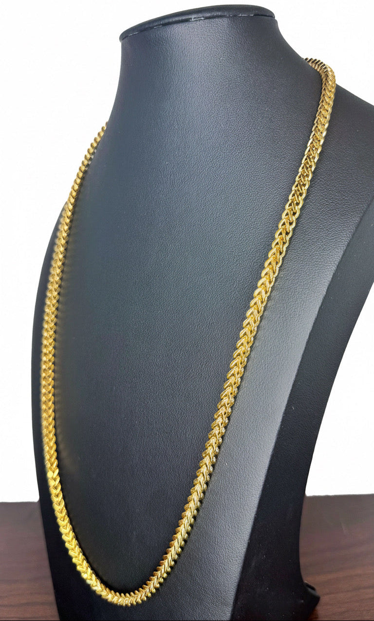 A gold-colored Franco chain necklace displayed on a black jewelry bust against a white background.