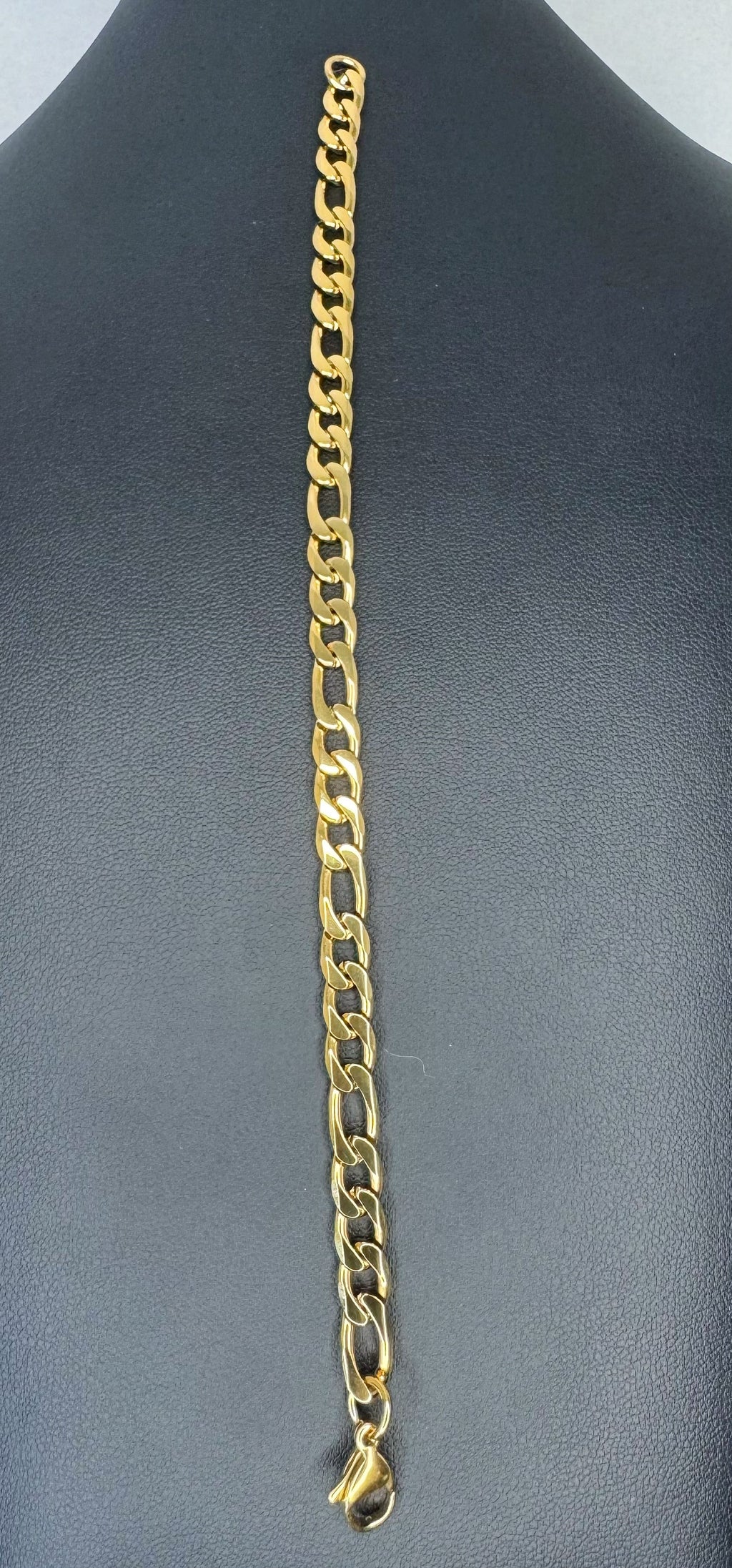 Gold chain necklace on a gray mannequin