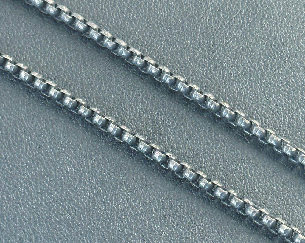 Close-up of a silver chain on a textured gray surface