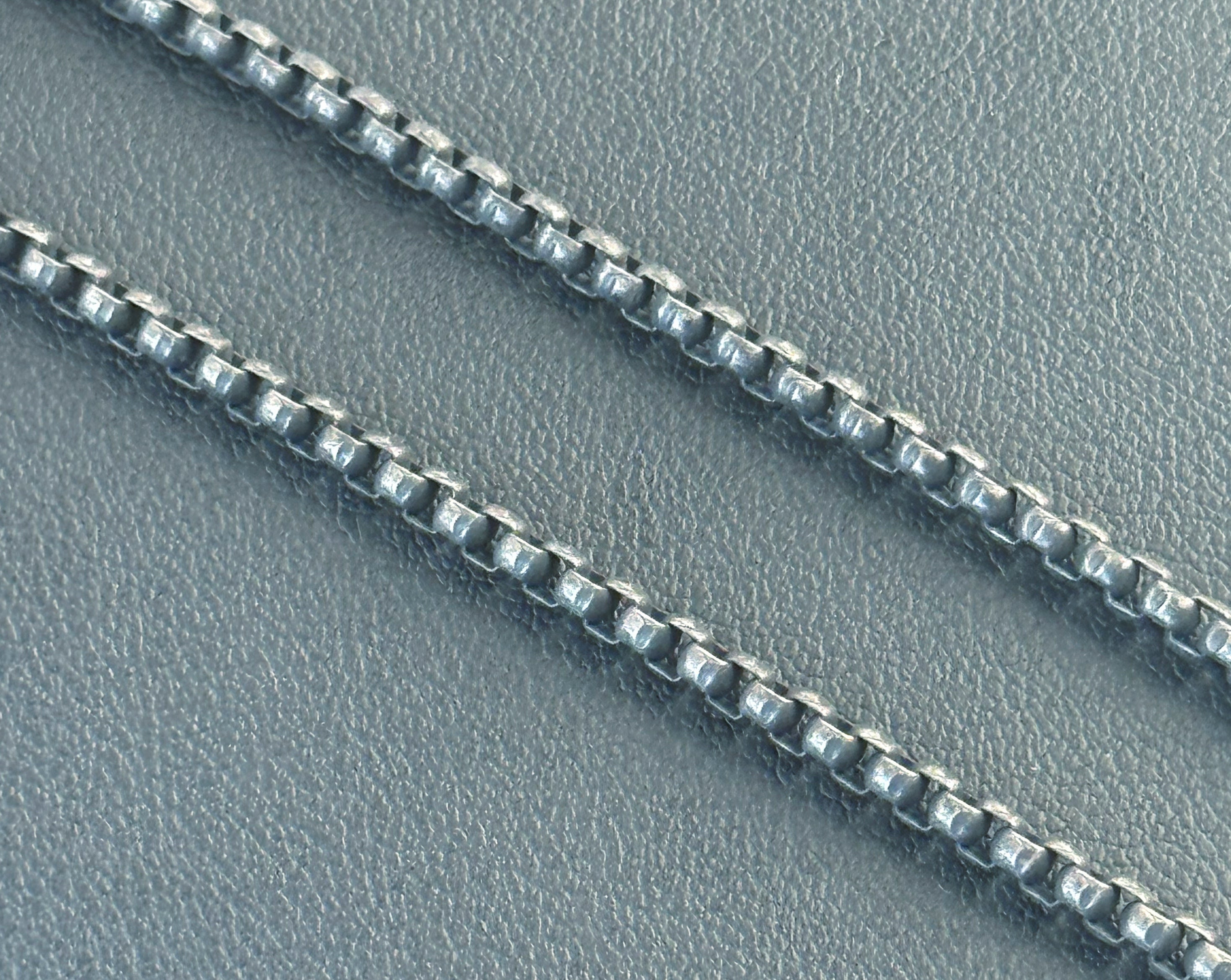 Close-up of a silver chain on a textured gray surface