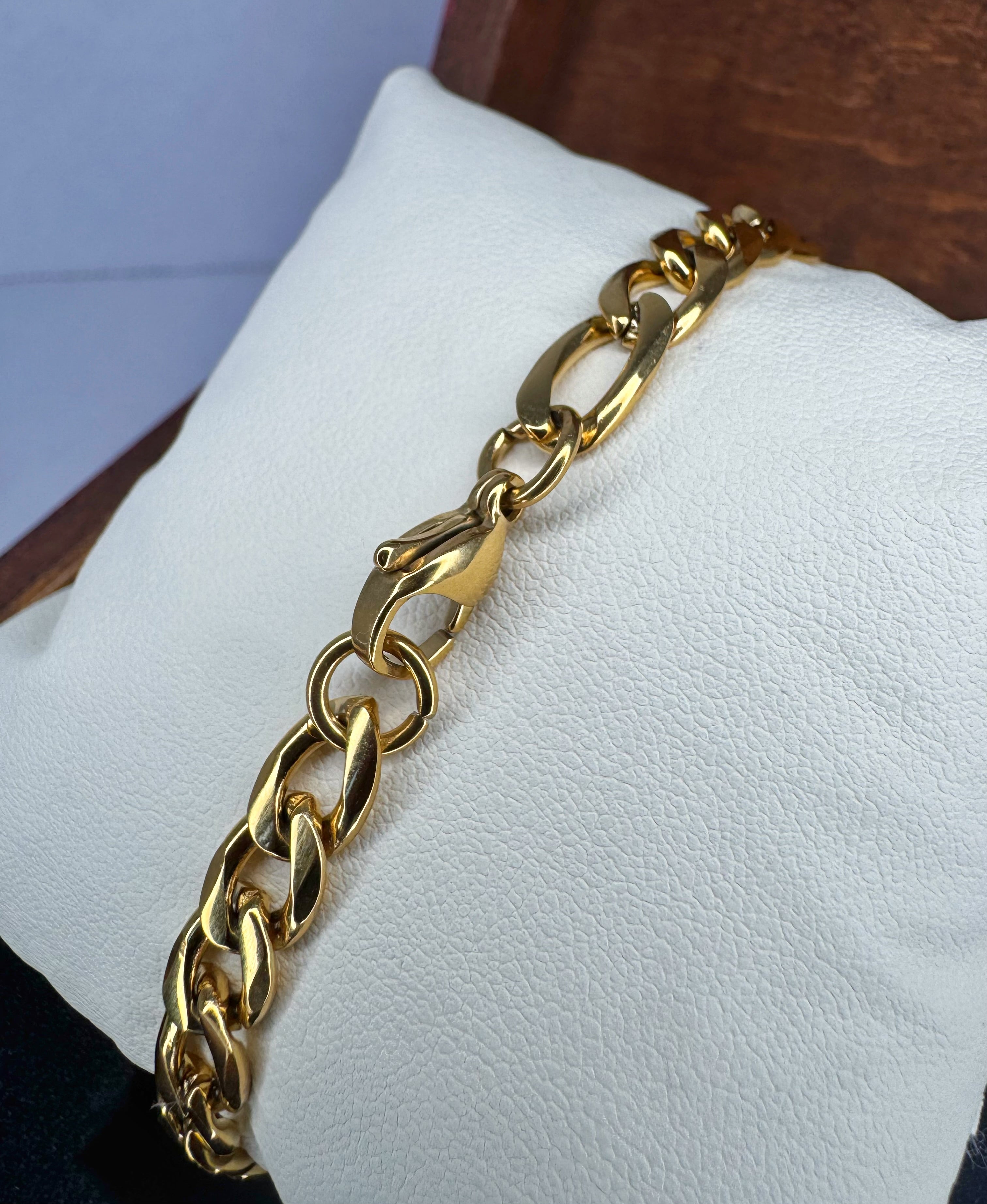 Gold chain bracelet on a white cushion with a blurred background