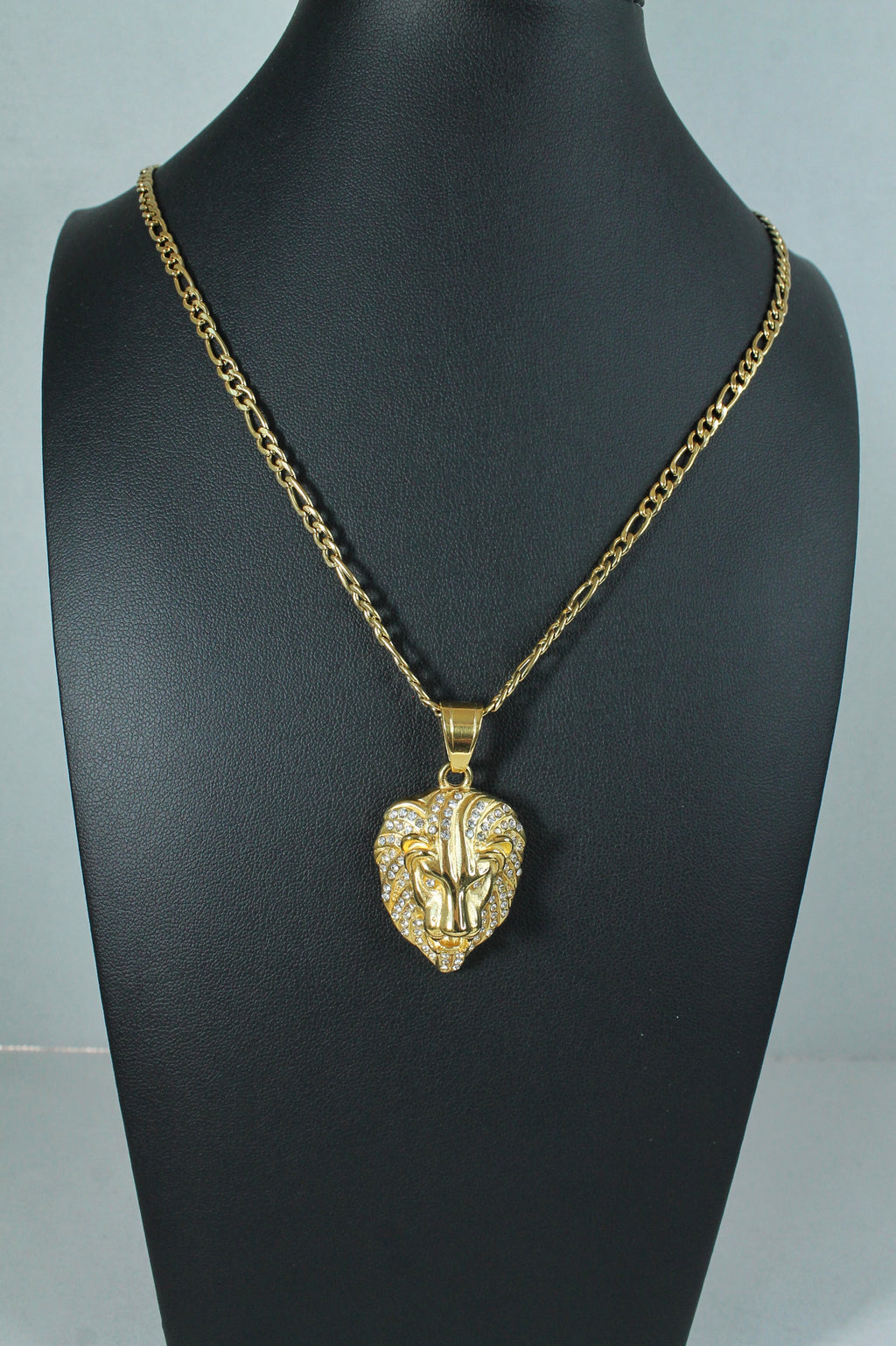 A gold lion head pendant necklace displayed on a black mannequin bust against a light gray background.