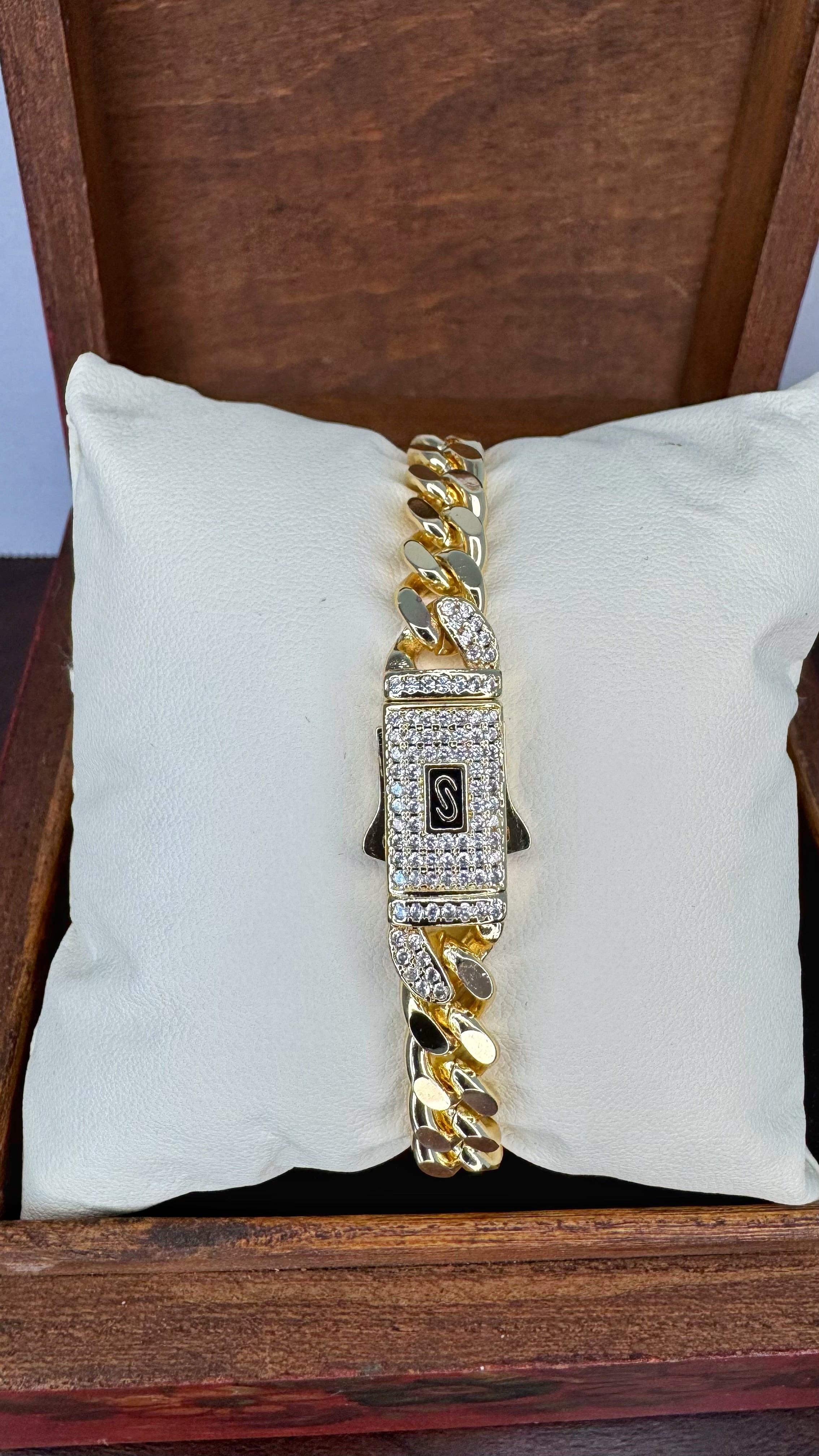 Gold bracelet with diamond accents on a white cushion inside a wooden box