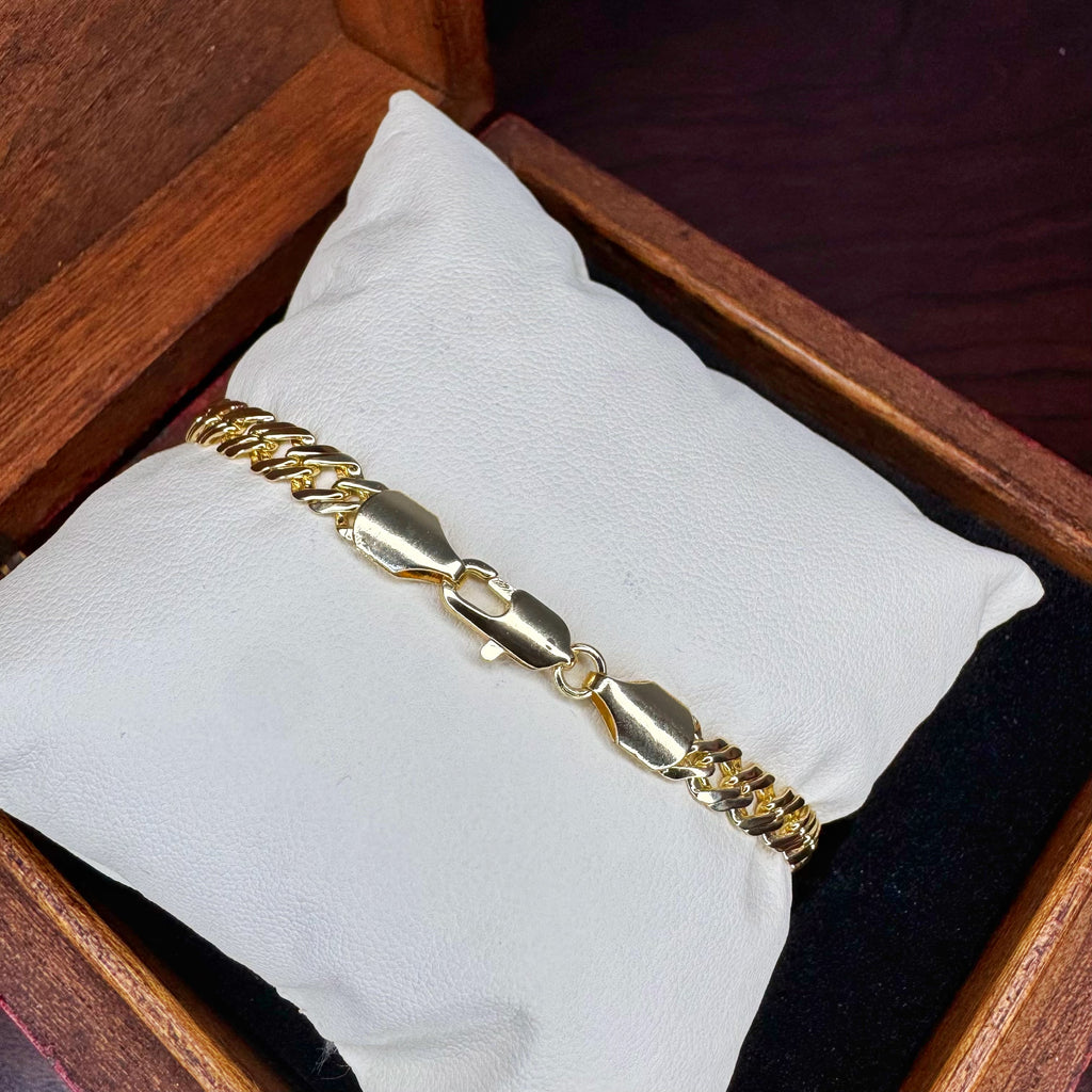 Gold bracelet on a white cushion inside a wooden box