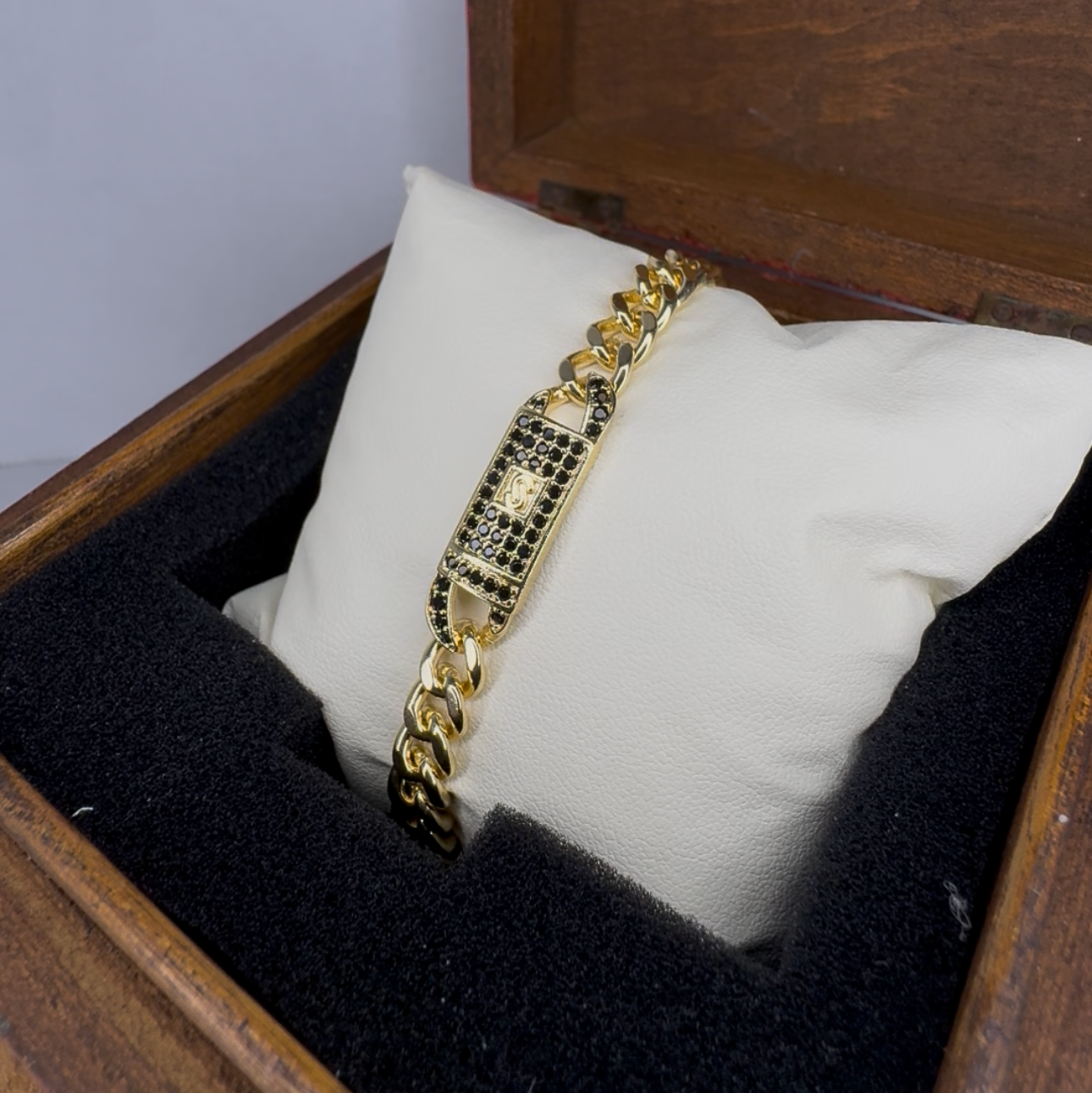 Gold bracelet in a wooden box with a white cushion