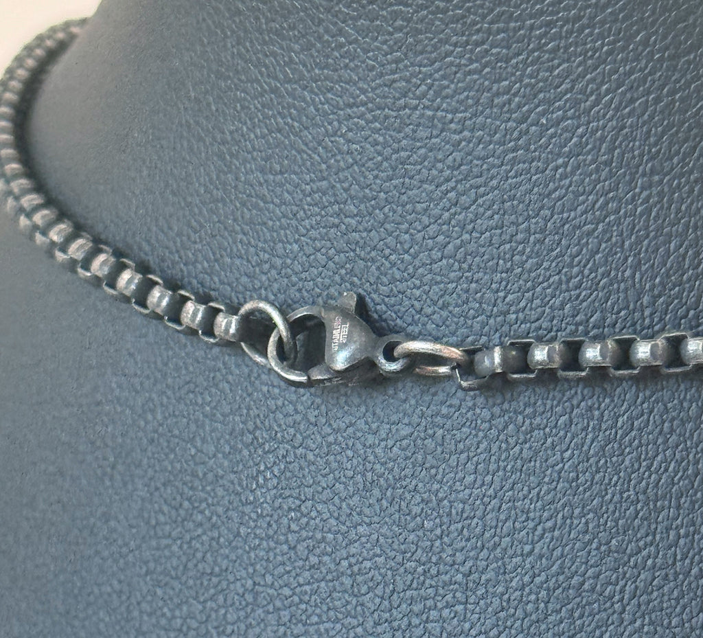 Silver chain necklace on a textured gray surface