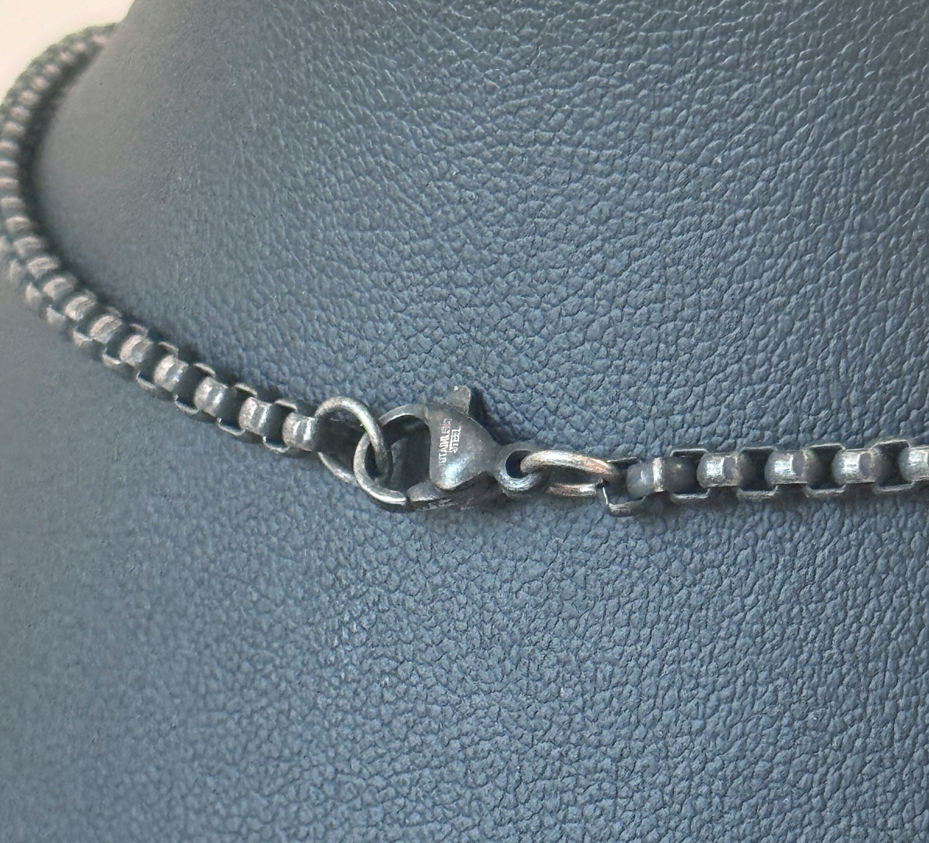 Silver chain necklace on a textured gray surface