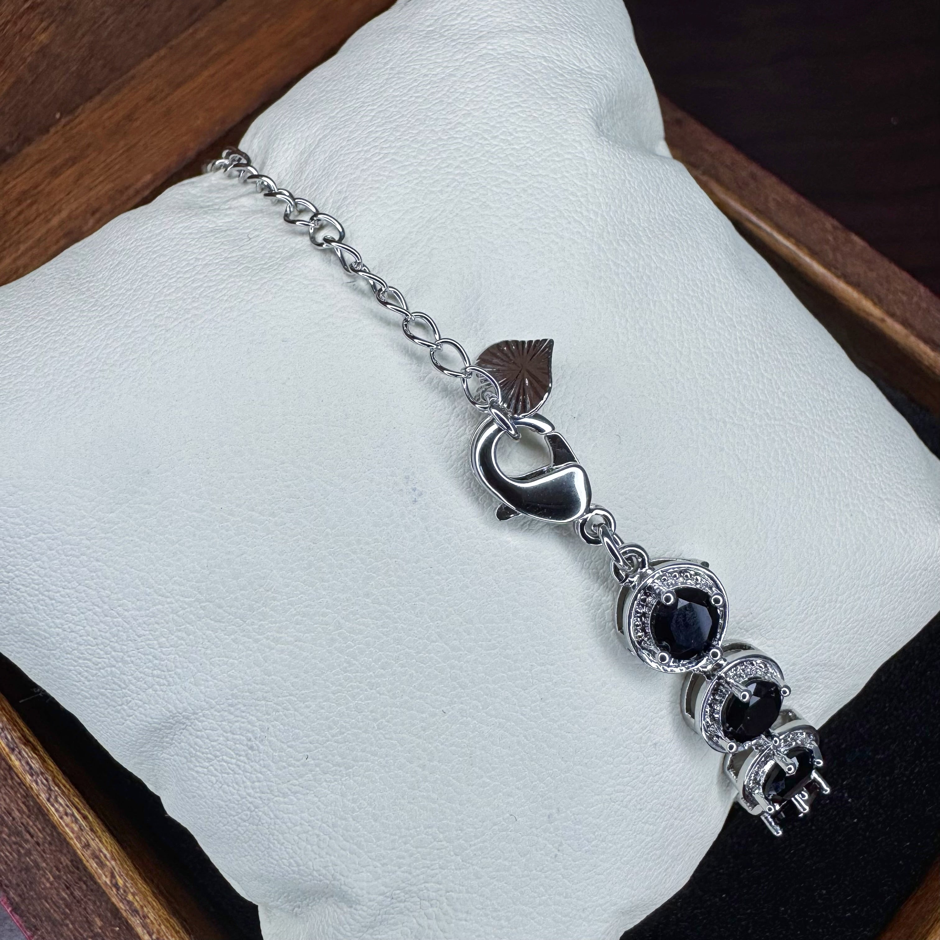 Silver bracelet with black stones on a white cushion