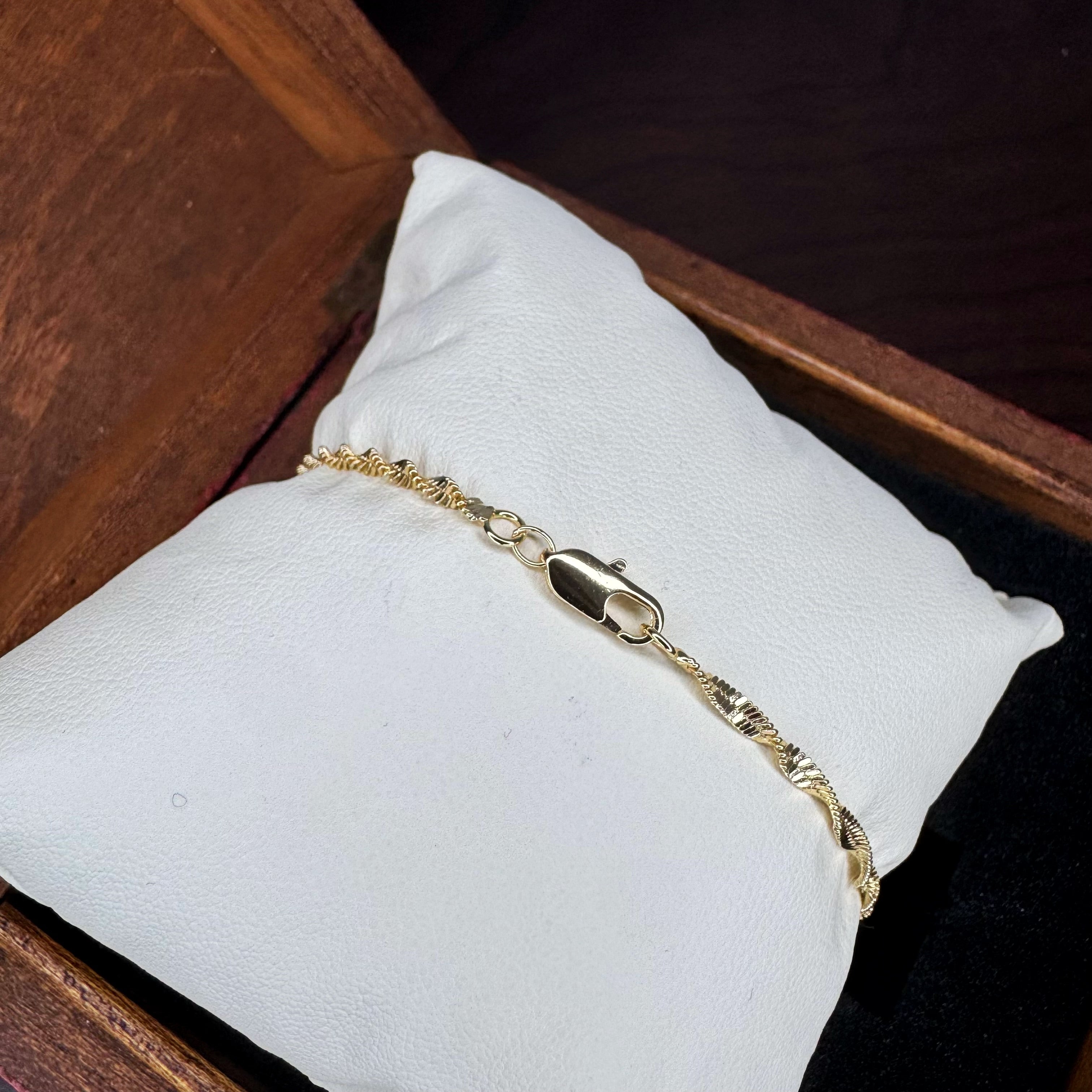 Gold bracelet on a white cushion with a wooden background