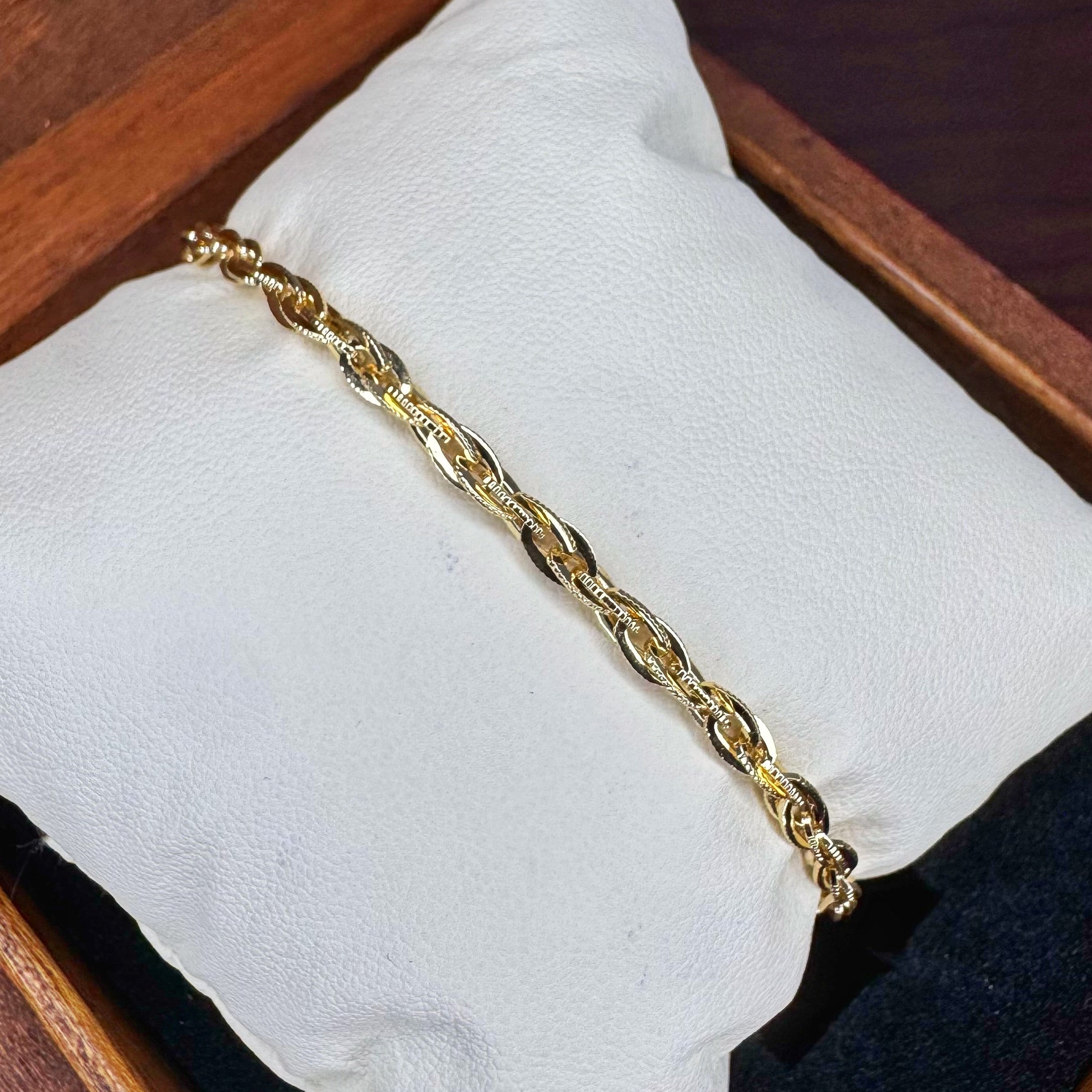 Gold chain bracelet on a white cloth with a wooden background