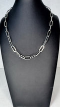 A silver paperclip chain necklace displayed on a black jewelry bust against a light gray background.