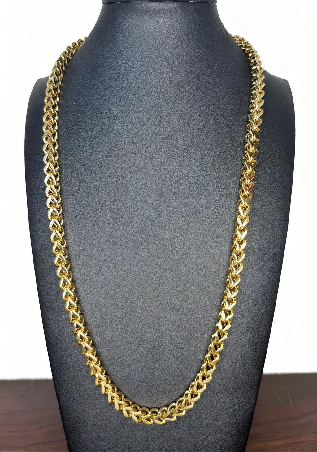 A thick gold Franco link chain necklace displayed on a black jewelry bust against a white background.