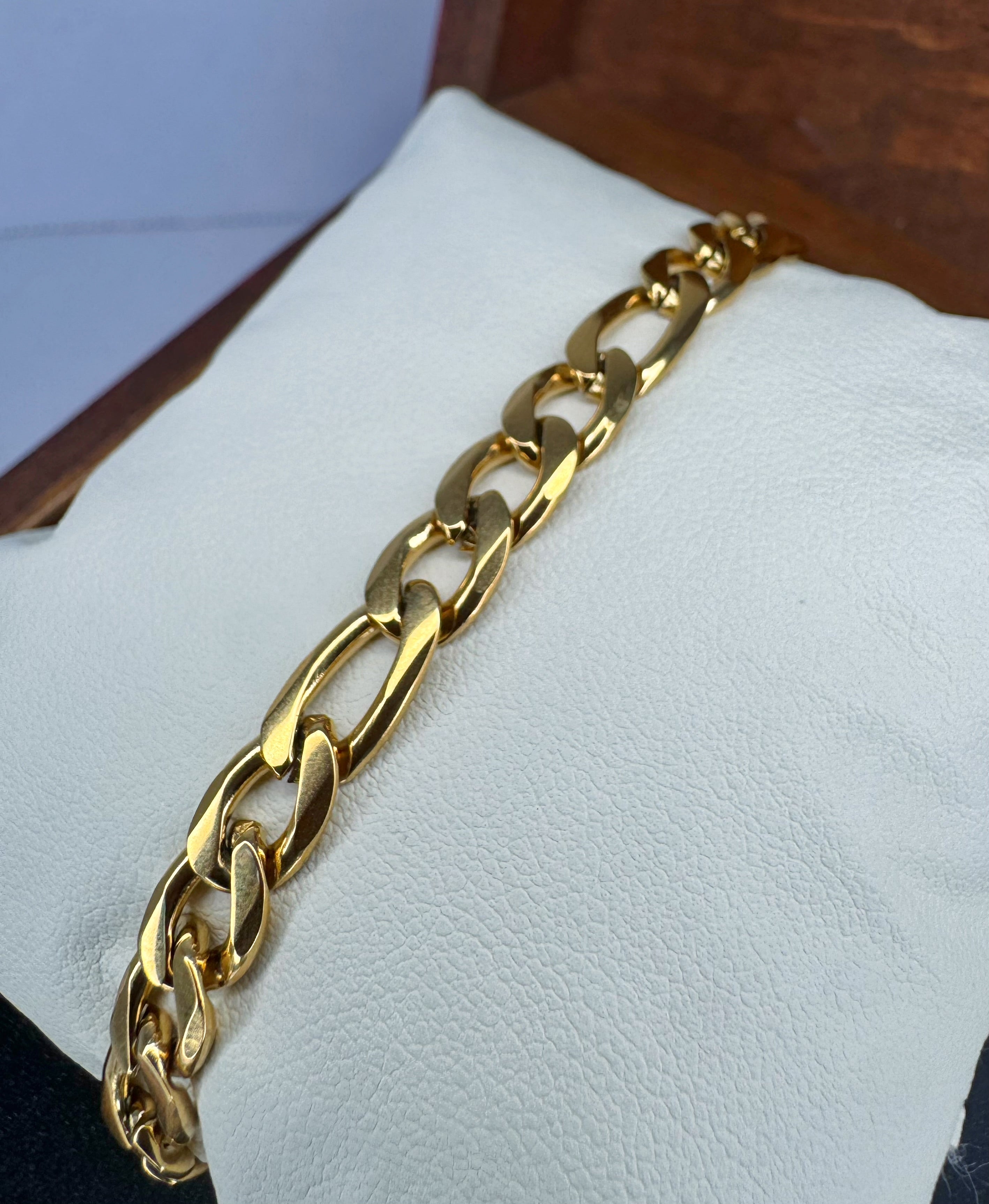 Gold chain bracelet on a white cushion with a wooden background