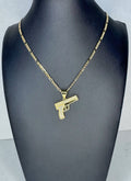 Gold gun-shaped pendant on a chain displayed on a mannequin neck.