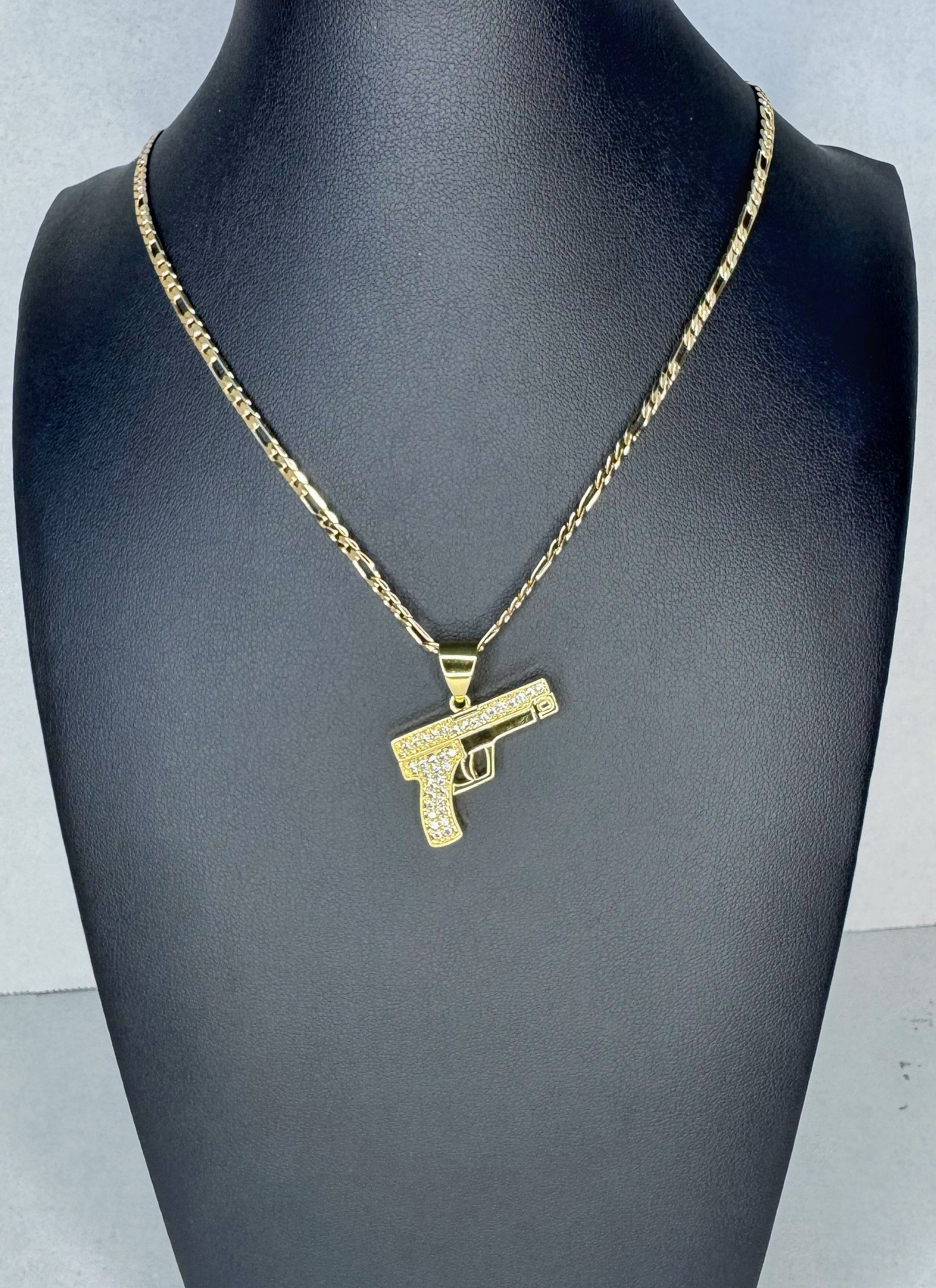 Gold gun-shaped pendant on a chain displayed on a mannequin neck.