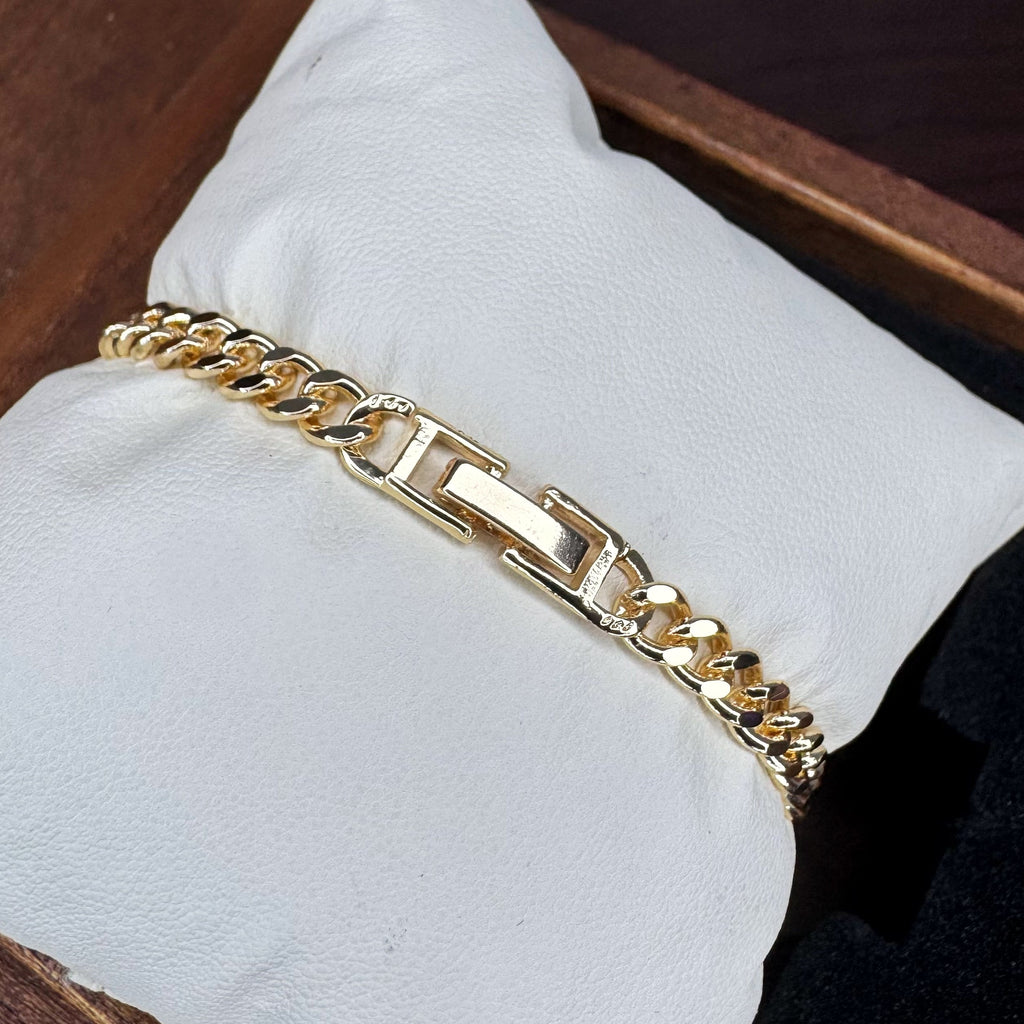 Gold chain bracelet on a white cushion with a wooden background