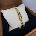 Gold bracelet in a wooden jewelry box with a white cushion