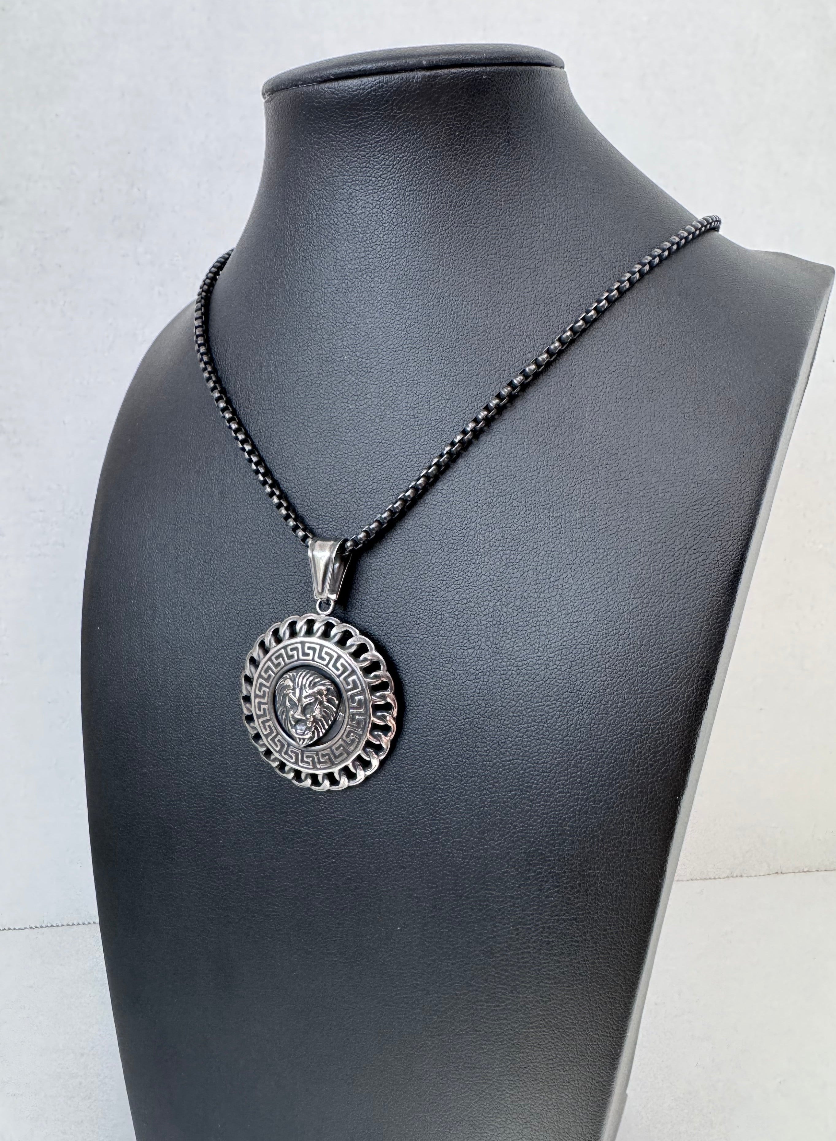 Black leather choker with a decorative silver lion pendant on a mannequin neck.