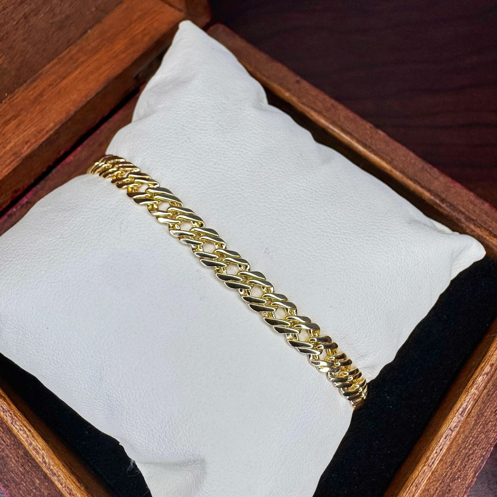 Gold chain bracelet on a white cushion inside a wooden box