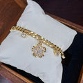 Gold bracelet with floral charms on a white pillow