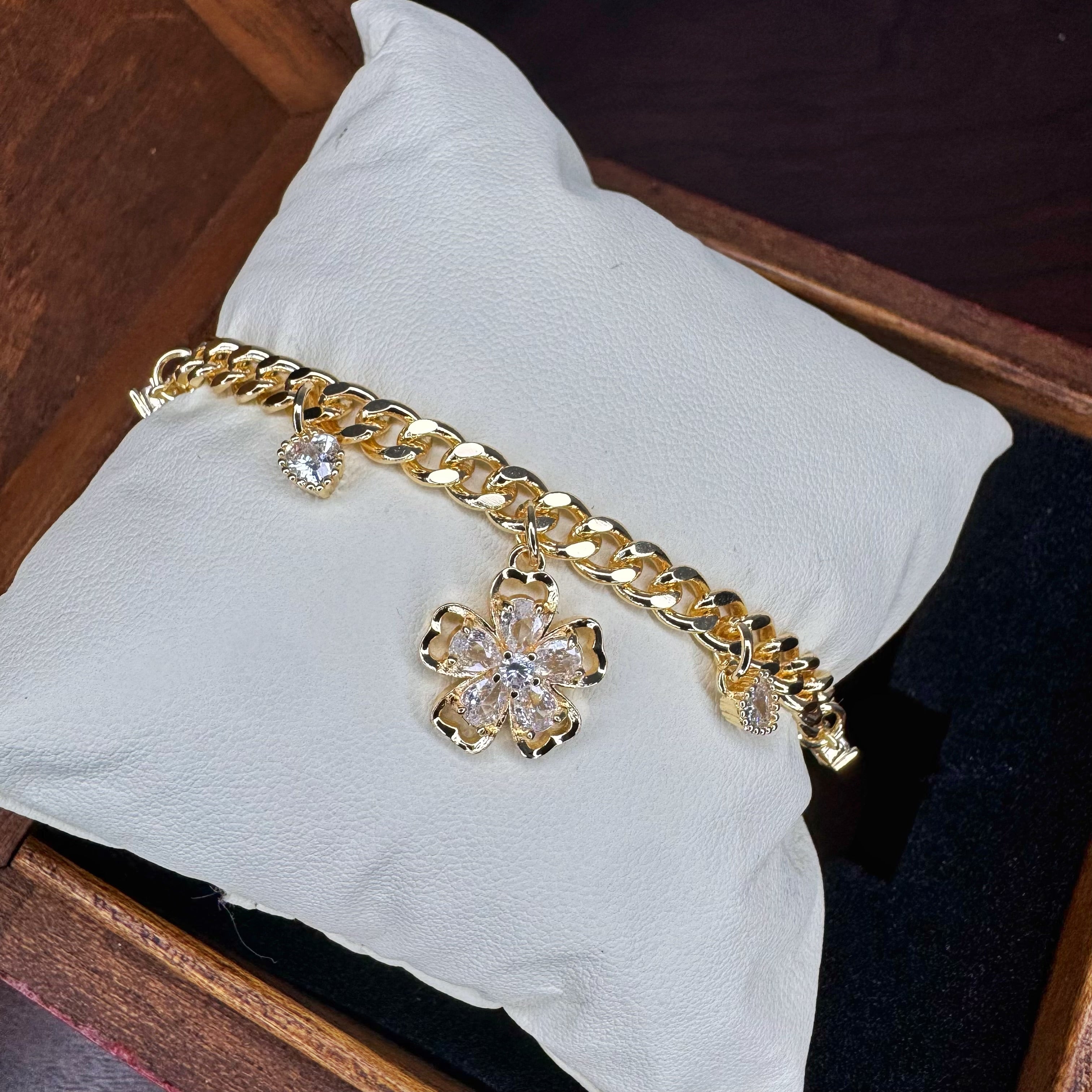 Gold bracelet with floral charms on a white pillow