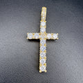 A yellow gold cross pendant adorned with clear cubic zirconia stones, displayed on a textured black surface.