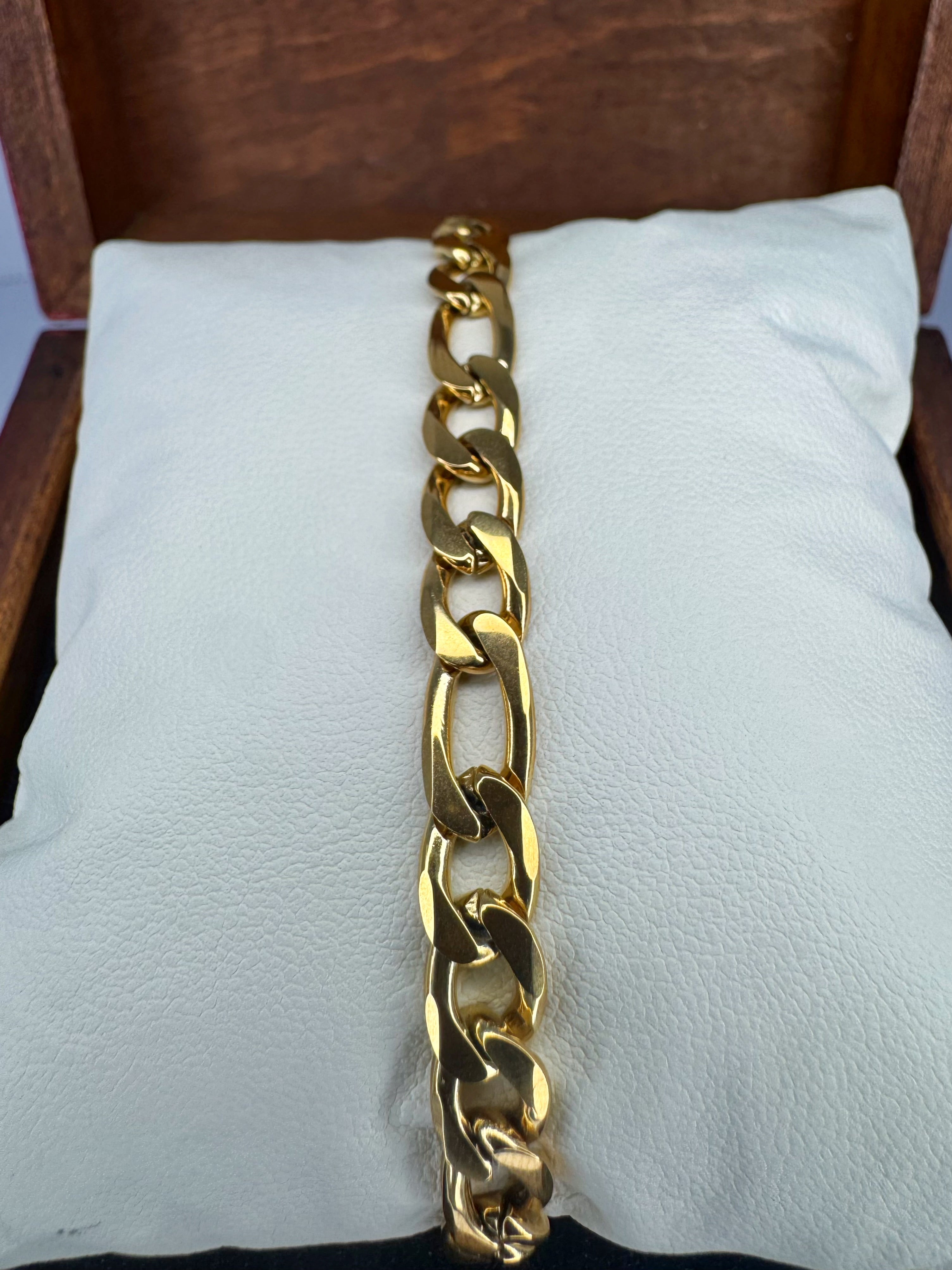 Gold chain bracelet on a white cushion with a wooden background