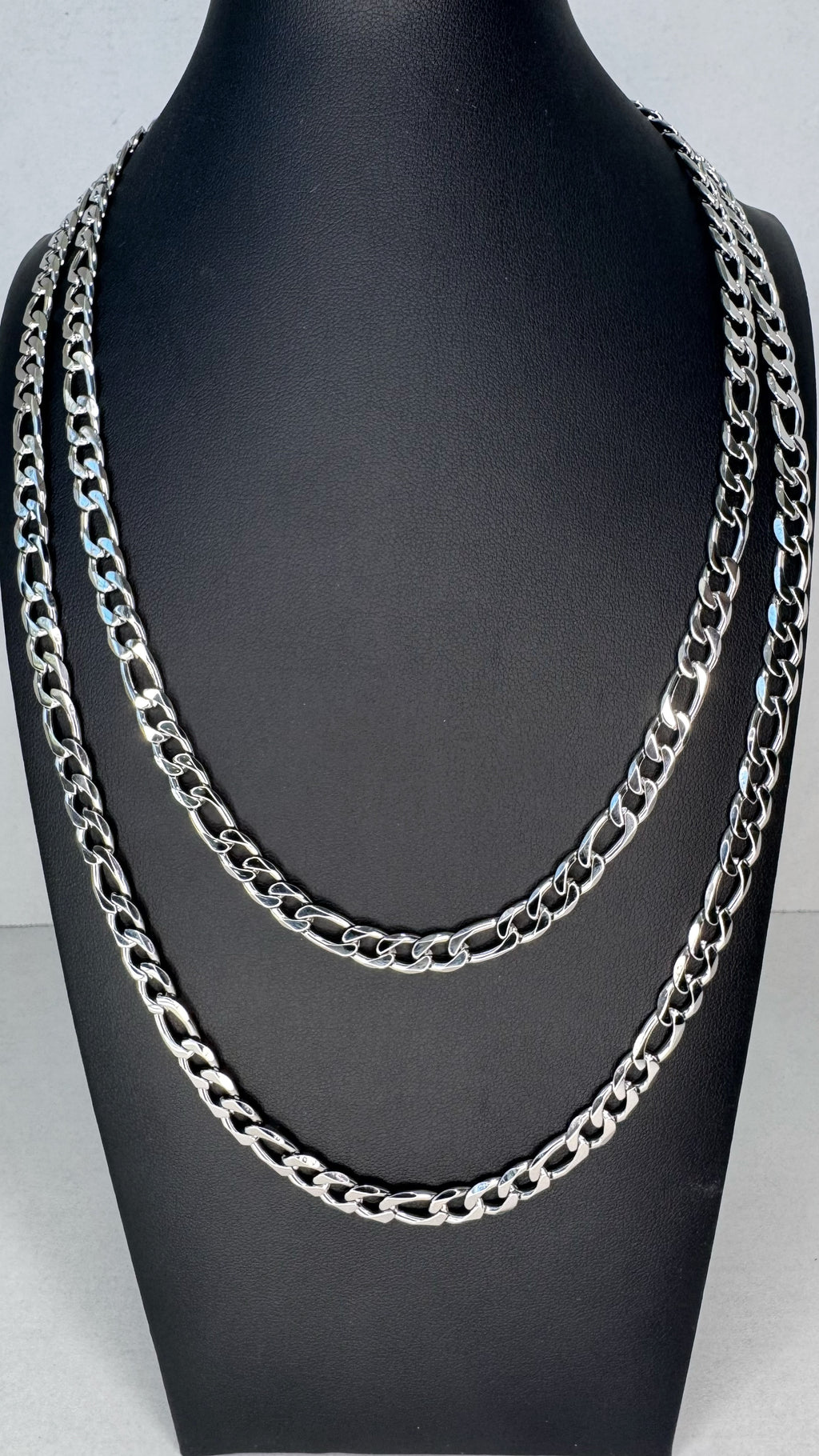 Two layered silver-tone Frigaro chain necklaces displayed on a black mannequin bust against a light gray background.
