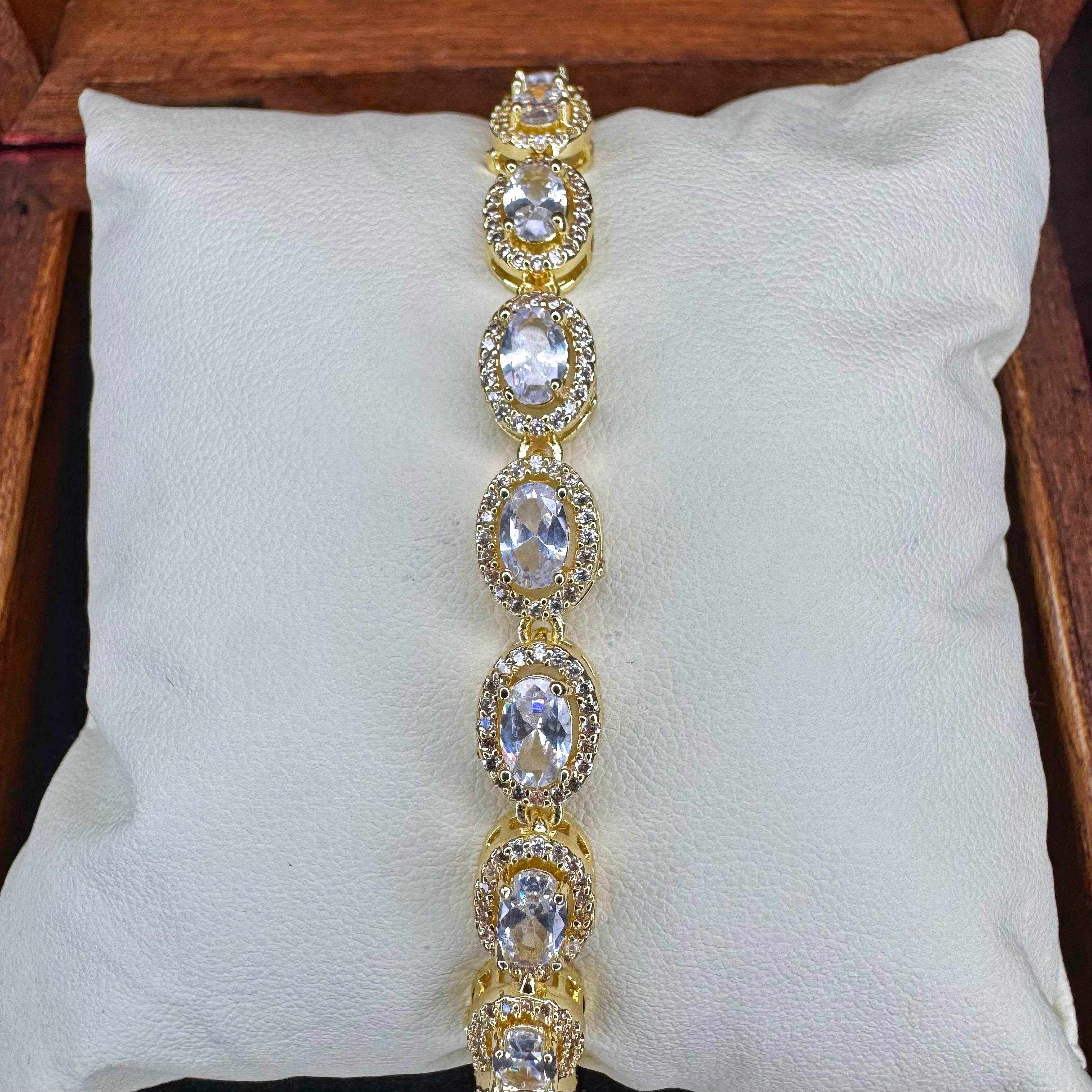 Gold bracelet with clear stones on a white cushion
