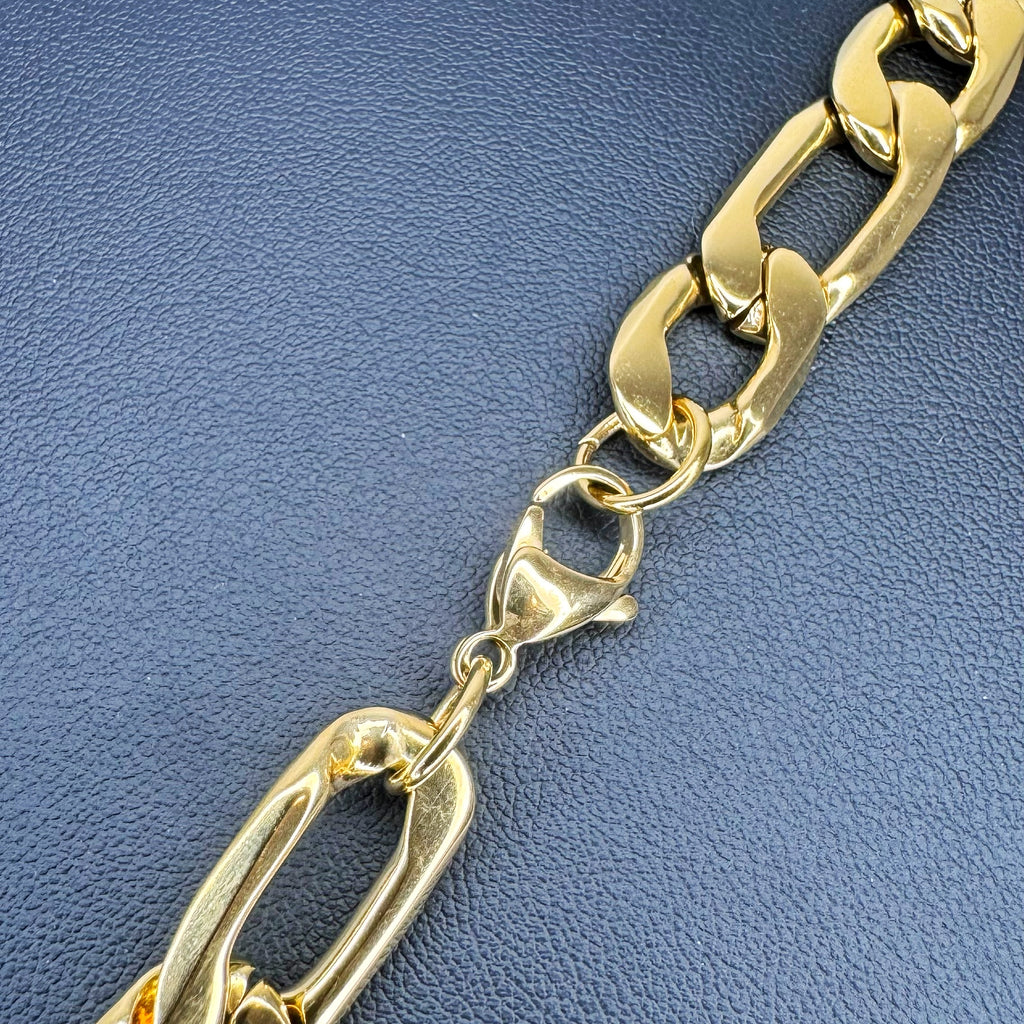 A close-up of a polished gold-tone chunky Figaro chain link bracelet on a textured blue background.
