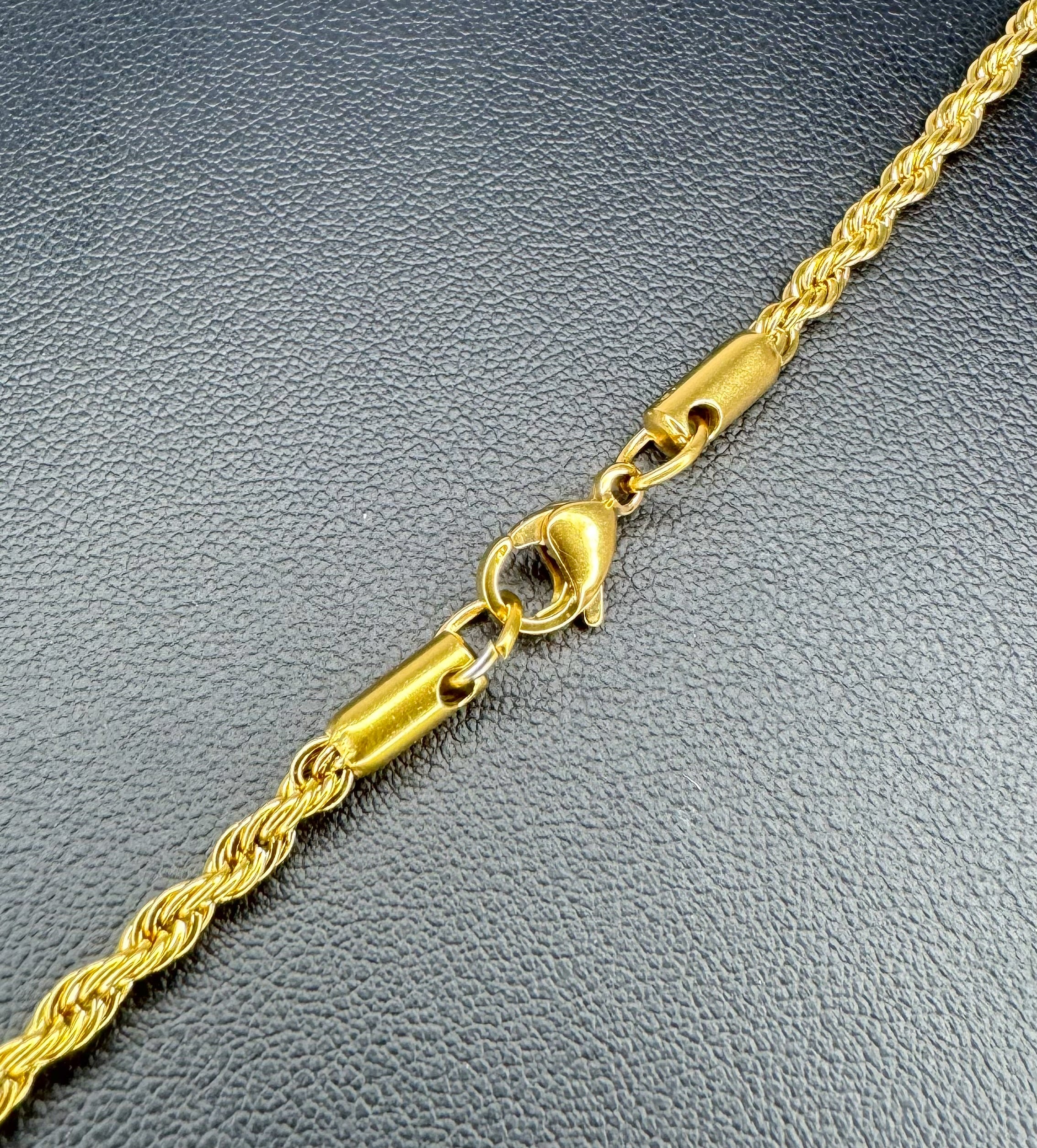 Gold rope chain necklace on a textured gray surface