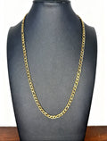 A gold-colored Figaro link chain necklace displayed on a matte black jewelry bust against a white background.