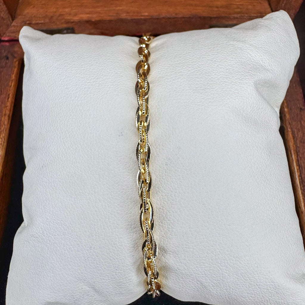 Gold chain bracelet on a white cushion with a wooden background