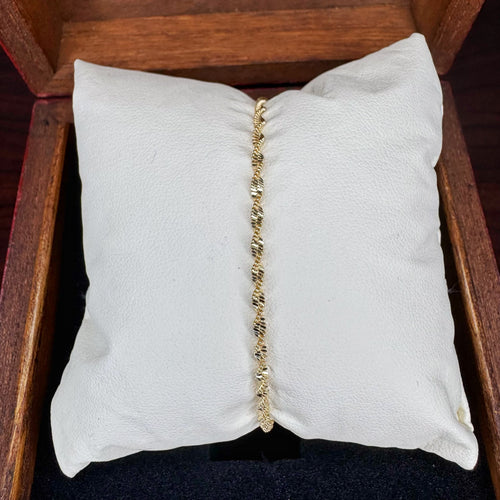 Gold bracelet on a white cushion inside a wooden box