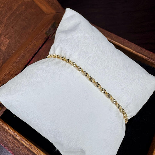 Gold bracelet on a white cushion with a wooden background