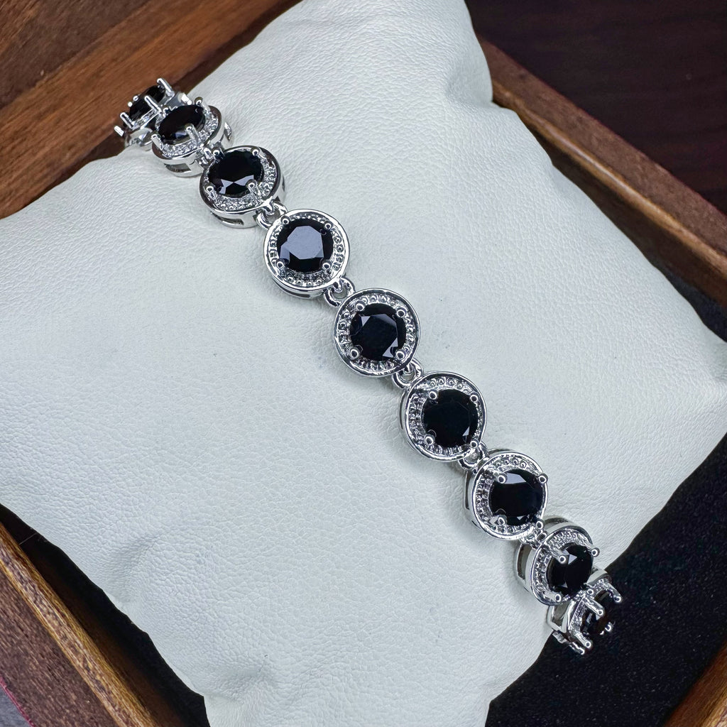 Silver bracelet with black gemstones on a white cushion