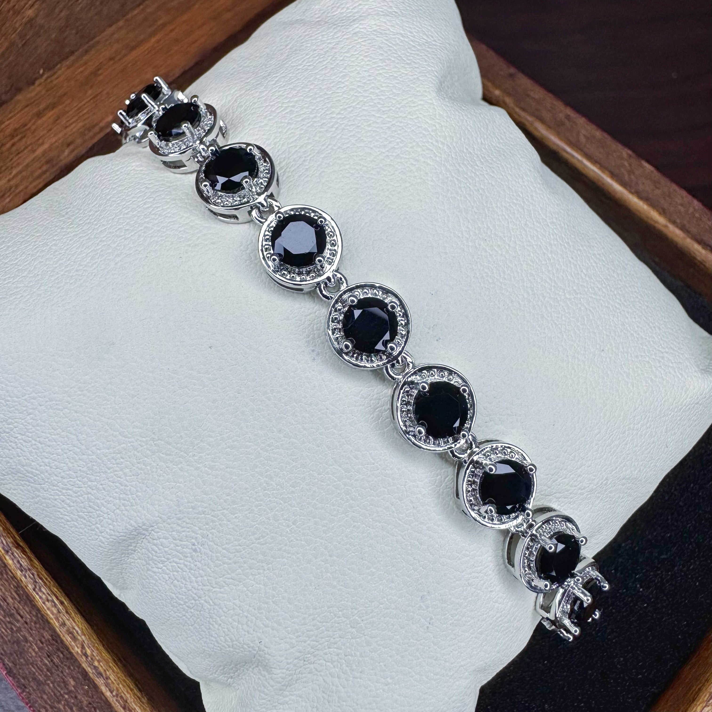 Silver bracelet with black gemstones on a white cushion