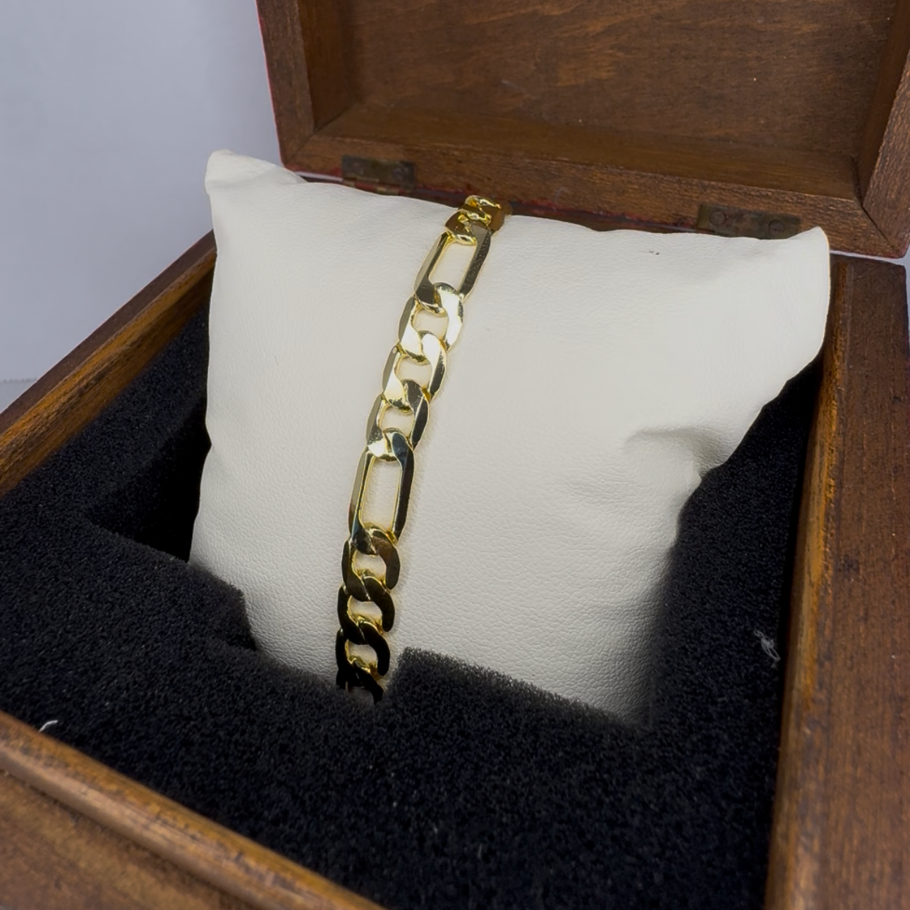 Gold bracelet in a wooden jewelry box with a white pillow