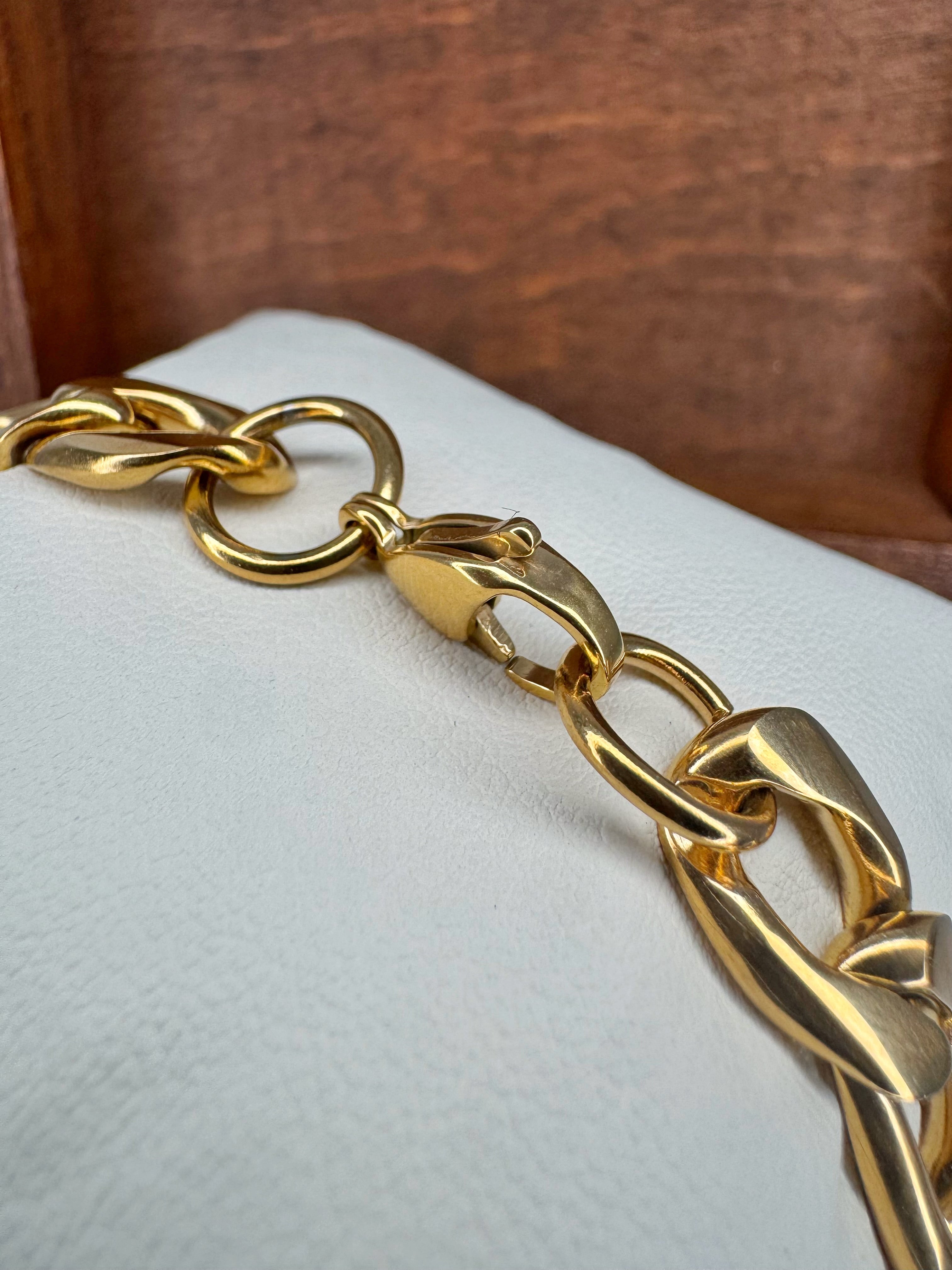 Gold chain bracelet on a white cushion with a wooden background