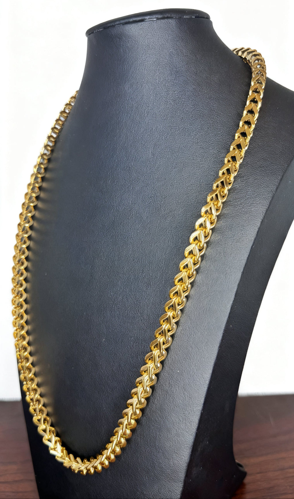 A chunky gold Franco link chain necklace displayed on a black mannequin bust against a white background.