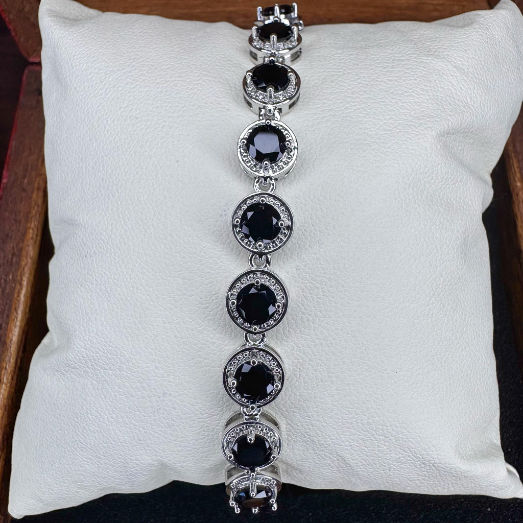 Silver bracelet with black gemstones on a white cushion