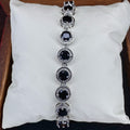 Silver bracelet with black gemstones on a white cushion