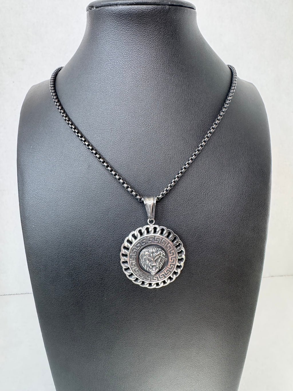 Silver chain with a decorative lion pendant on a mannequin against a white background