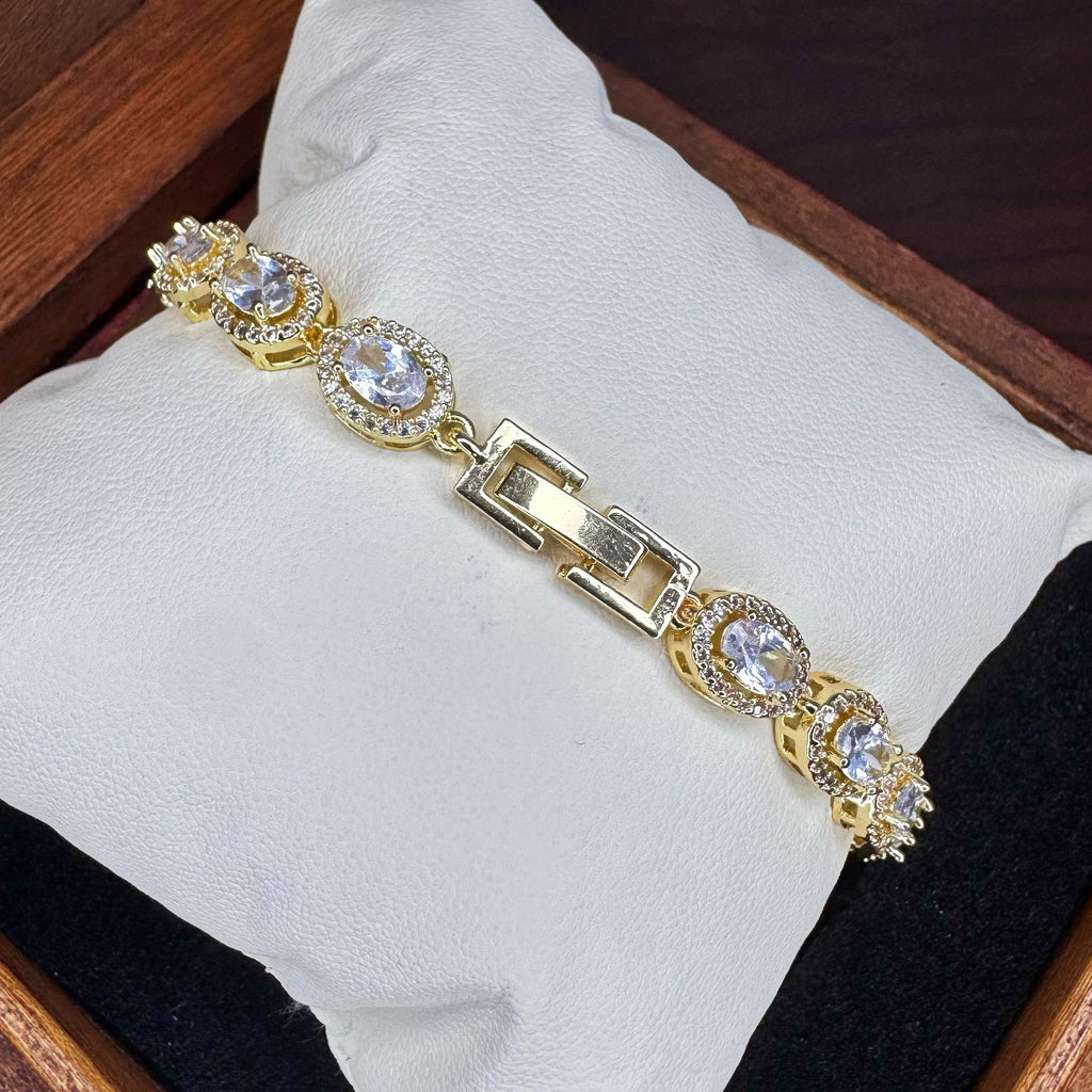 Gold bracelet with gemstones on a white cushion inside a wooden box