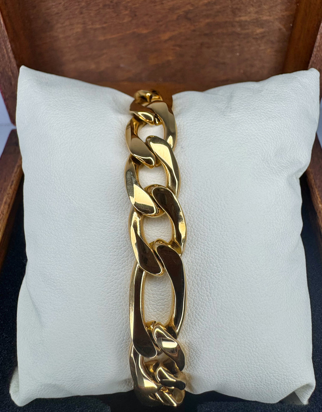 Gold chain bracelet on a white cushion with a wooden background
