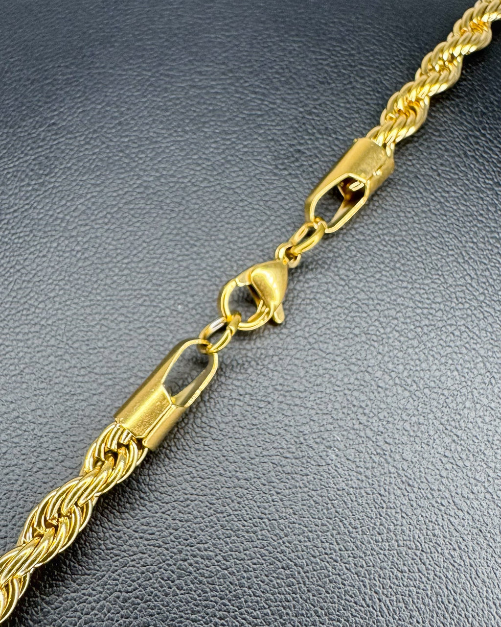 Gold rope chain necklace on a dark textured surface