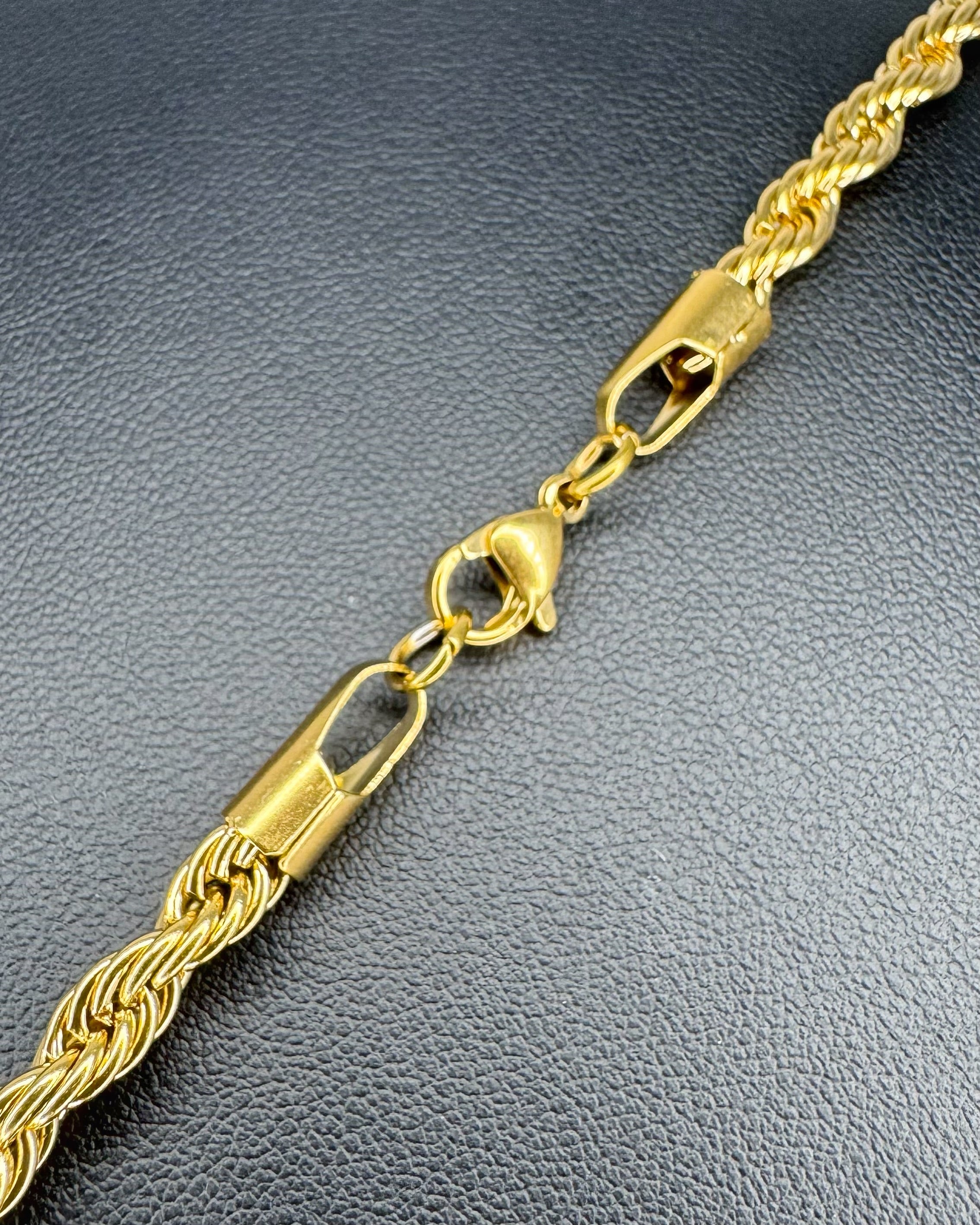 Gold rope chain necklace on a dark textured surface