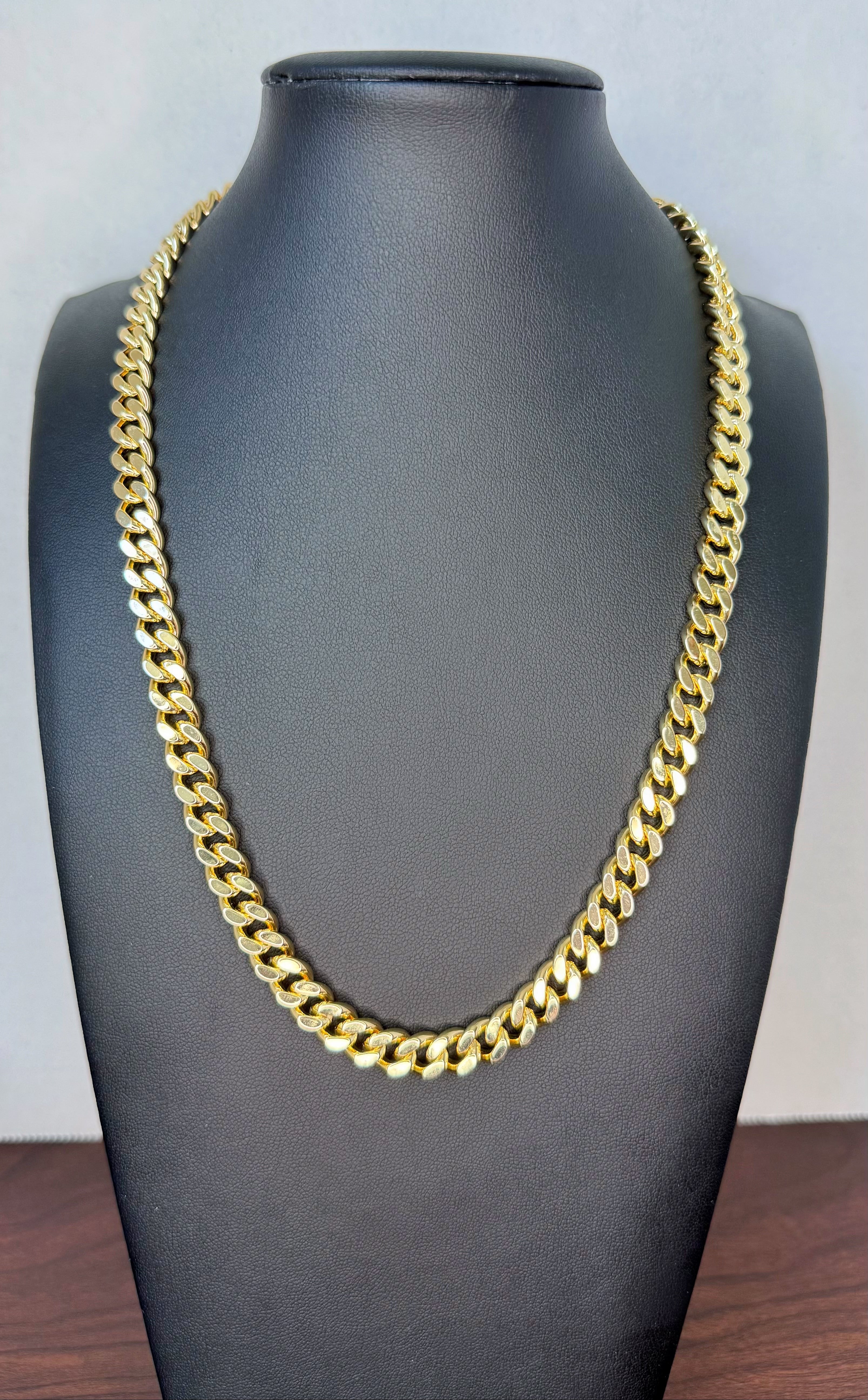 Gold chain necklace on a black mannequin bust against a light gray background